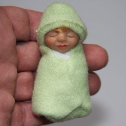 light green baby doll in hand