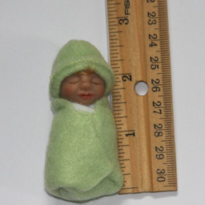 light green baby doll next to ruler