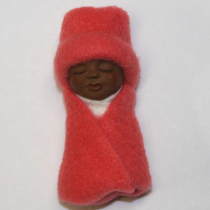 african baby doll dressed in coral colored fleece