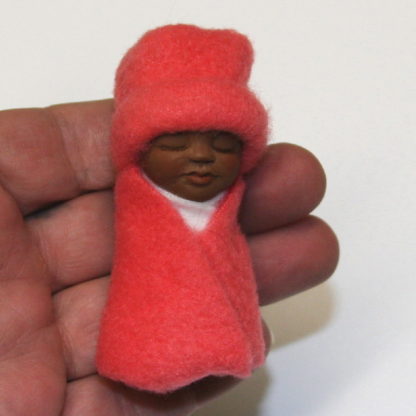 miniature african baby doll in hand