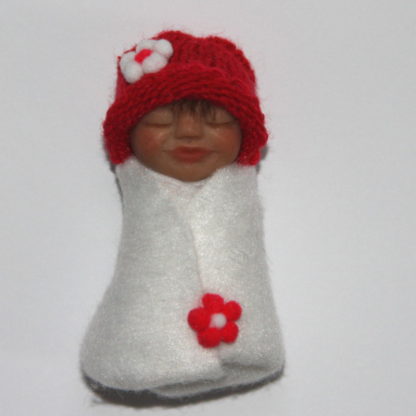 Miniature baby doll with red white wrap