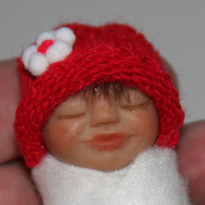miniature baby doll face with red hat