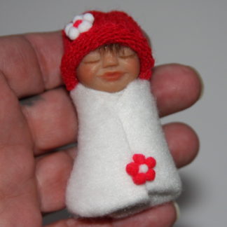 miniature baby doll in hand