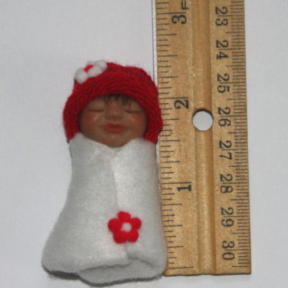 red flower baby doll next to ruler