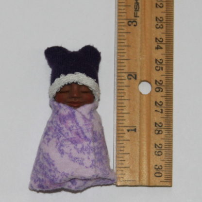 brown skin miniature baby doll and ruler