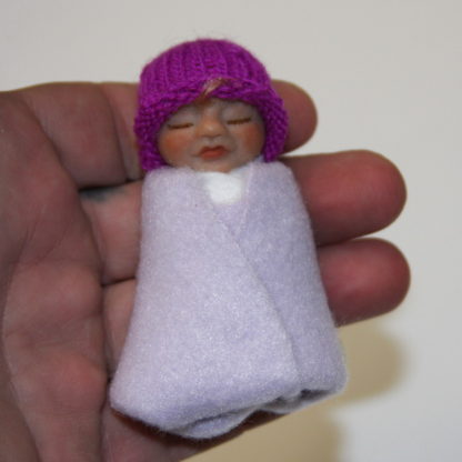 Miniature baby girl doll in hand