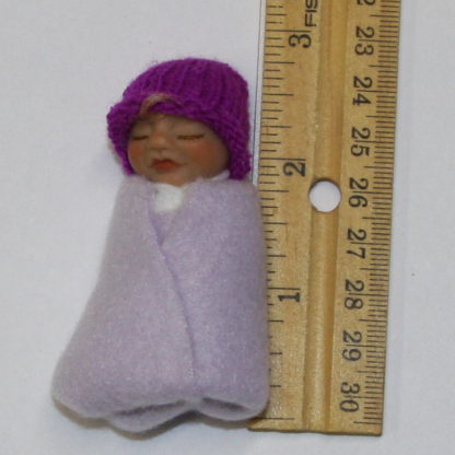 miniature baby girl doll next to ruler