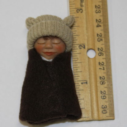 miniature baby boy doll next to ruler
