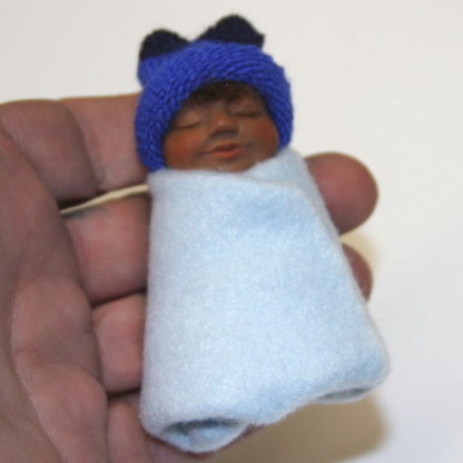 Ethnic baby boy doll in hand