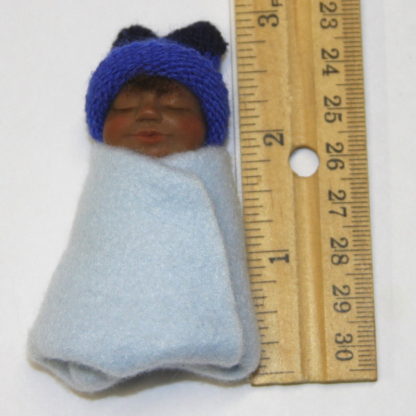miniature mexican baby boy doll next to ruler
