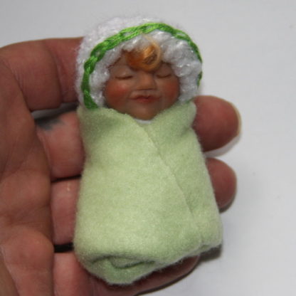 light green baby girl doll in hand