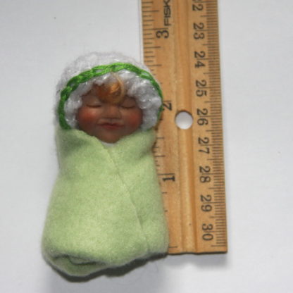 light green baby girl doll with ruler